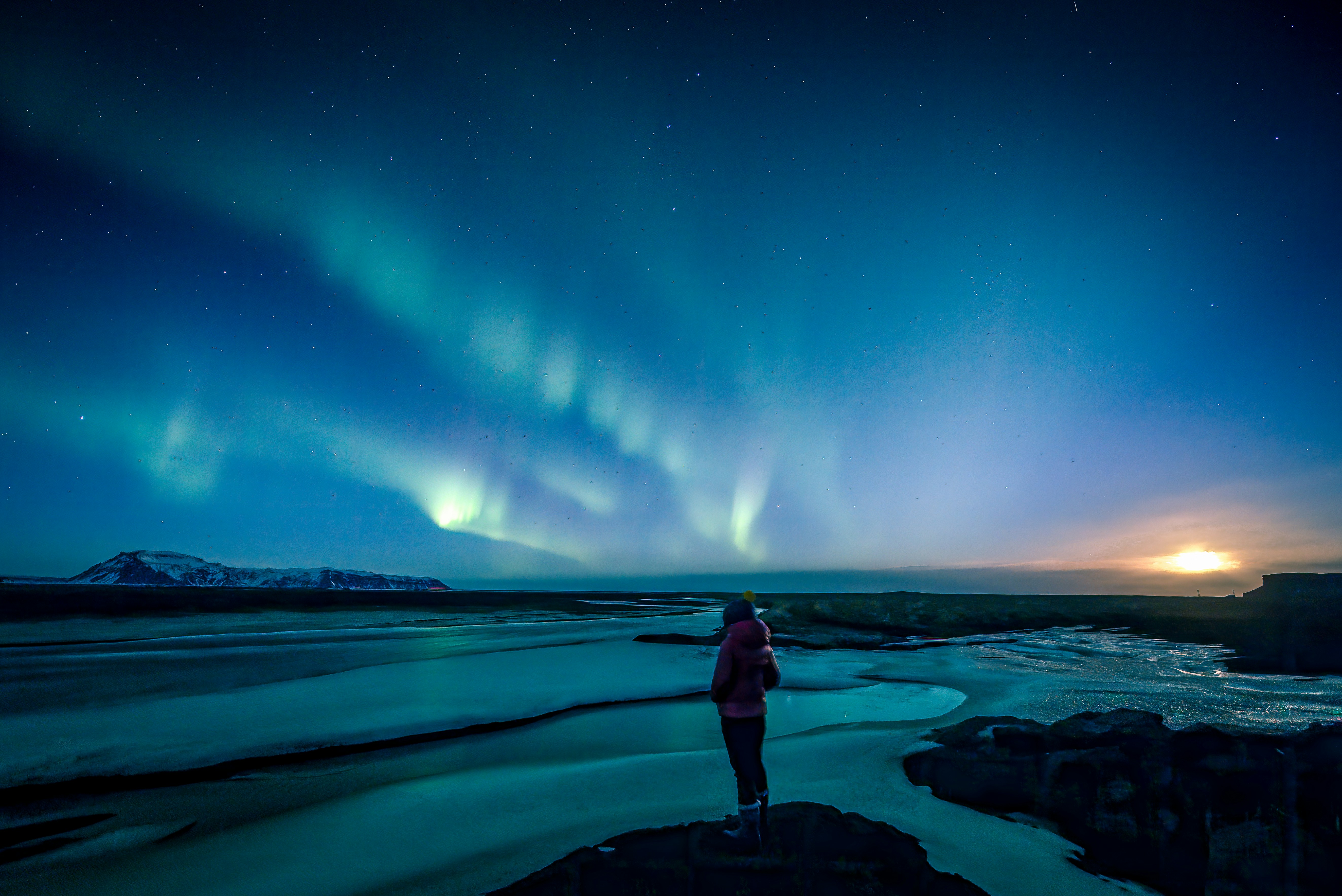 Vivid green Northern Lights aurora borealis dancing over snow-covered Icelandic mountains at night