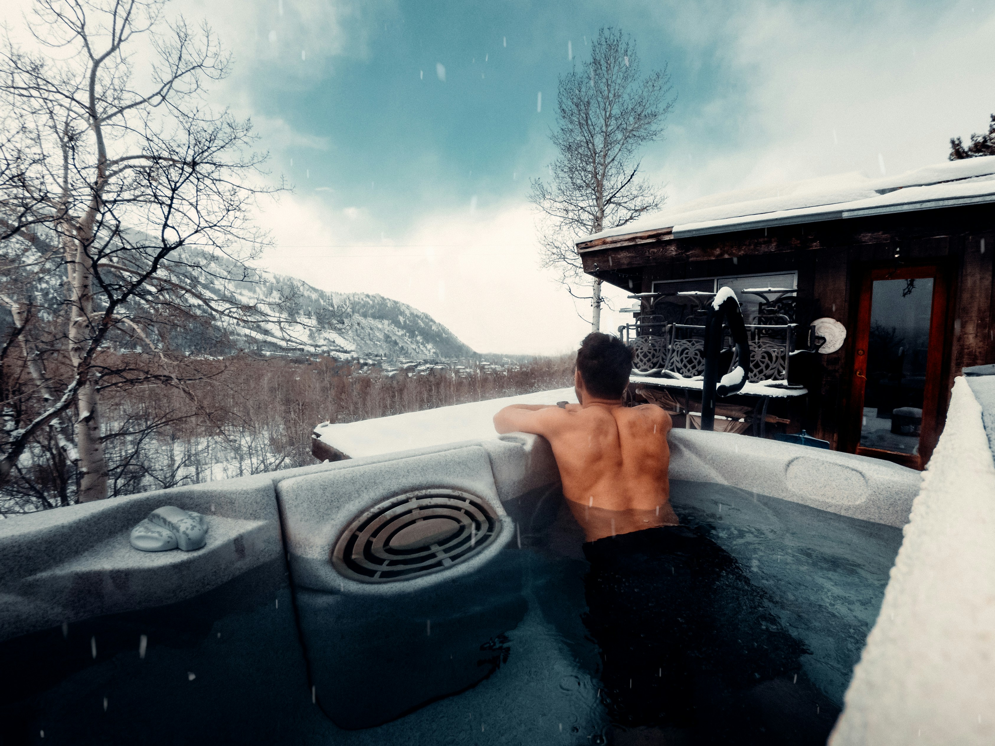 Steaming geothermal hot spots surrounded by snow with mountains in background under starry night sky