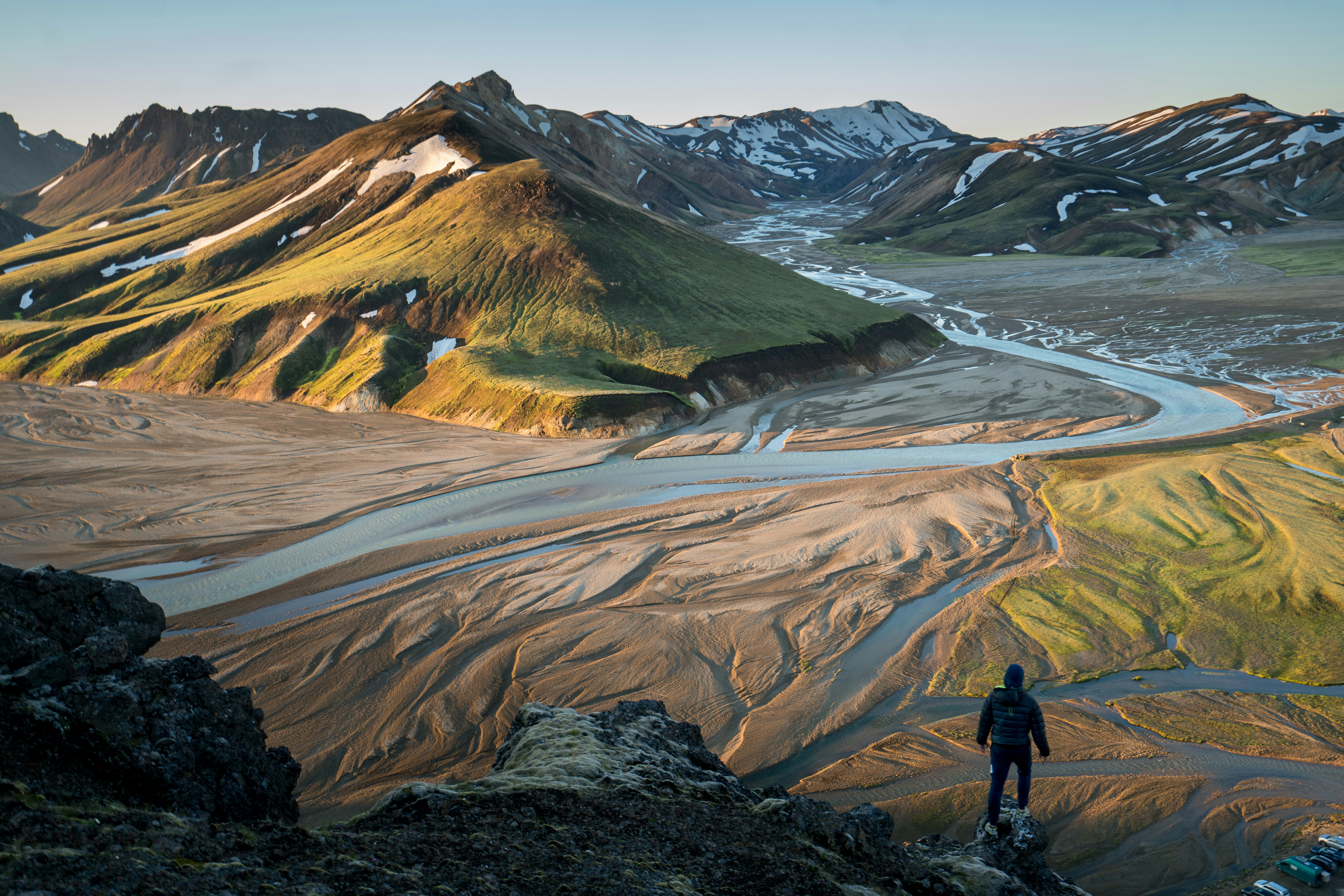 Vast Icelandic landscape with green moss-covered lava fields and distant snow-capped mountains