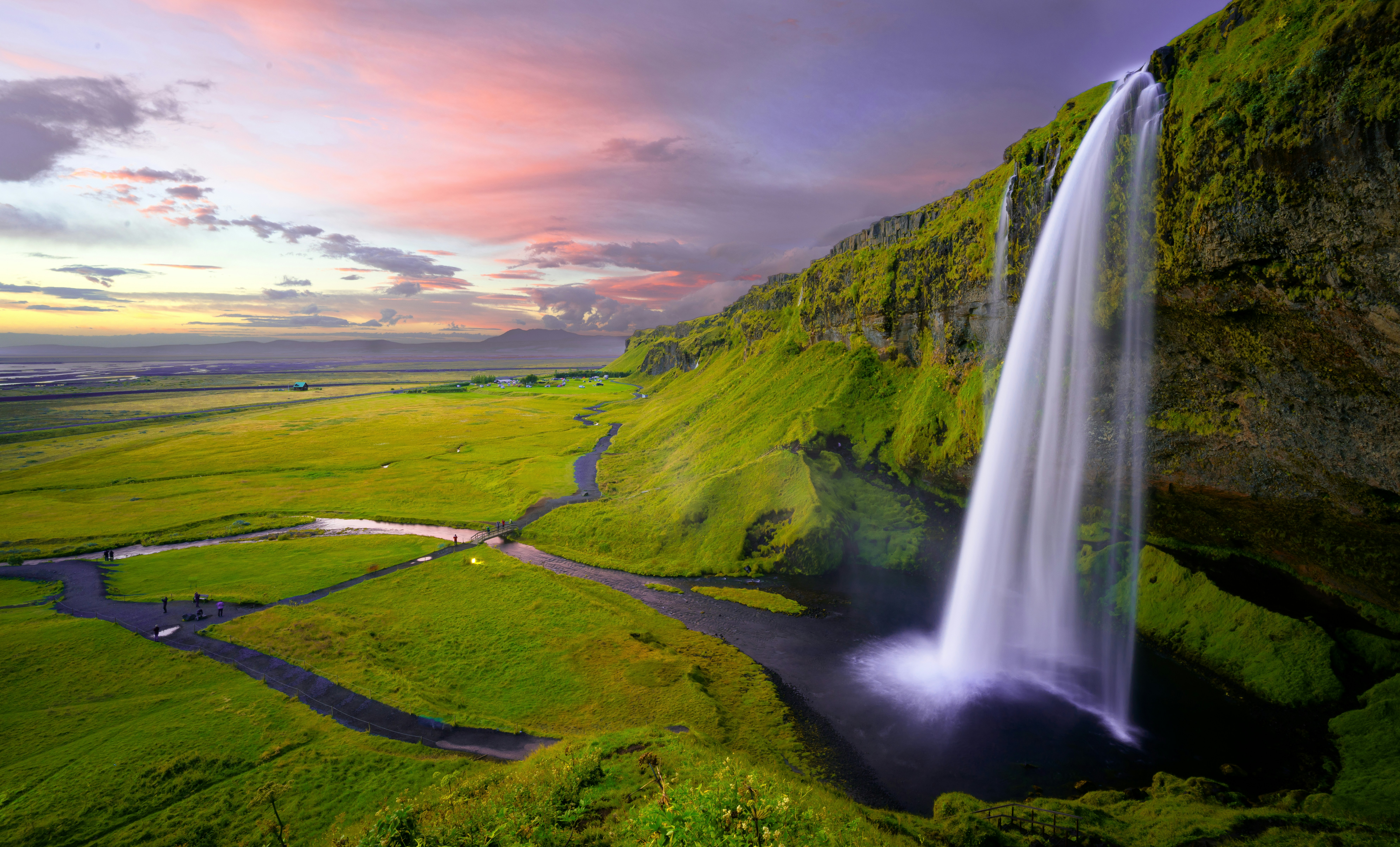 Powerful waterfall cascading down dark rocky cliffs in dramatic Icelandic landscape